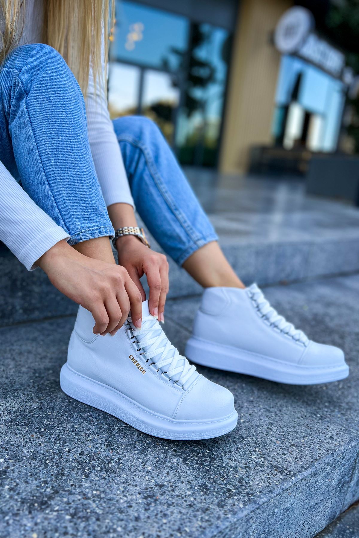 White lace-up boots on a stone step, side view with stitched laces