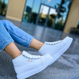 White lace-up boots with thick rubber sole, positioned on a concrete ledge