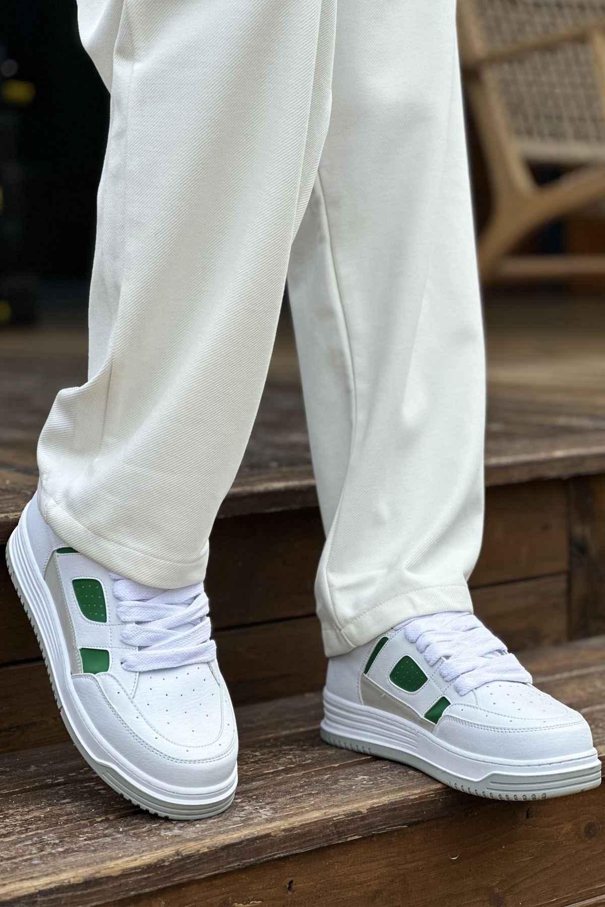 Men's white green low-top sneakers with thick sole, side view on wooden floor