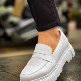 White loafer with side strap detail and chunky sole, worn with dark pants