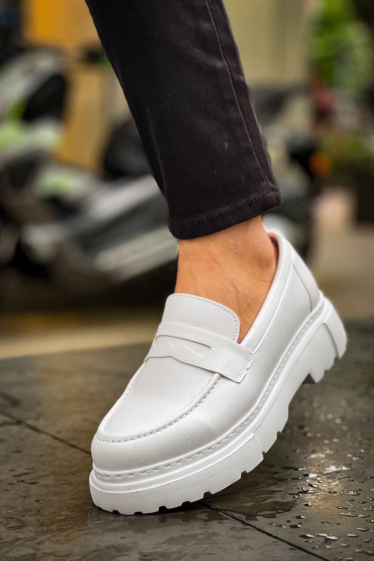 White loafer with side strap detail and chunky sole, worn with dark pants