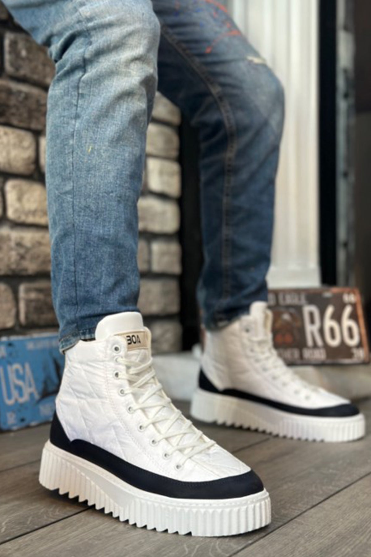 White high-top lace-up boots with black/ navy side panels and chunky rubber sole