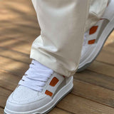 Men's white sneakers with orange side panels, lace-up design and gray rubber sole