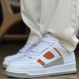 White lace-up sneakers with orange square logo on side and perforated toe