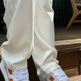 White sneakers with orange accents and thick gray sole, worn with white pants