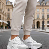 Men's white low-top sneakers, lace-up with chunky sole and side logo.