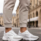 White lace-up sneakers with chunky soles and side branding.
