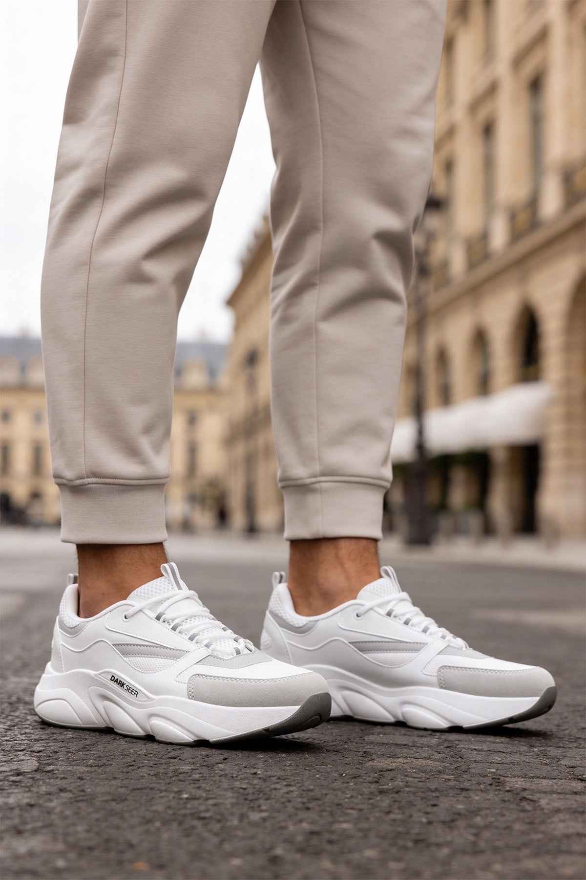 White lace-up sneakers with chunky soles and side branding.