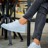 White low-top lace sneakers worn with denim jeans cuffs