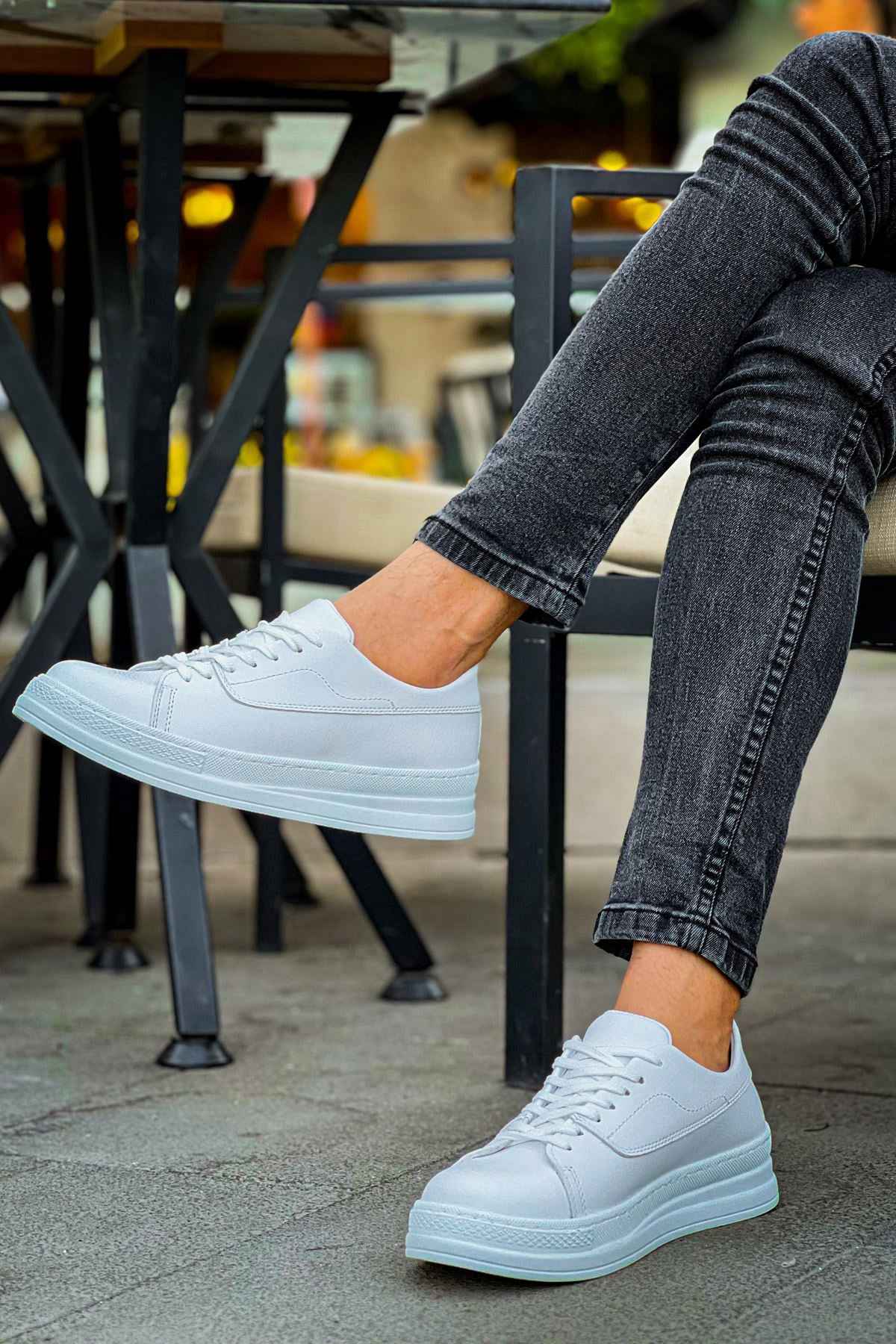 White low-top lace sneakers worn with denim jeans cuffs