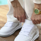 Men's white sneakers on feet with lace-up closure and perforated toe box