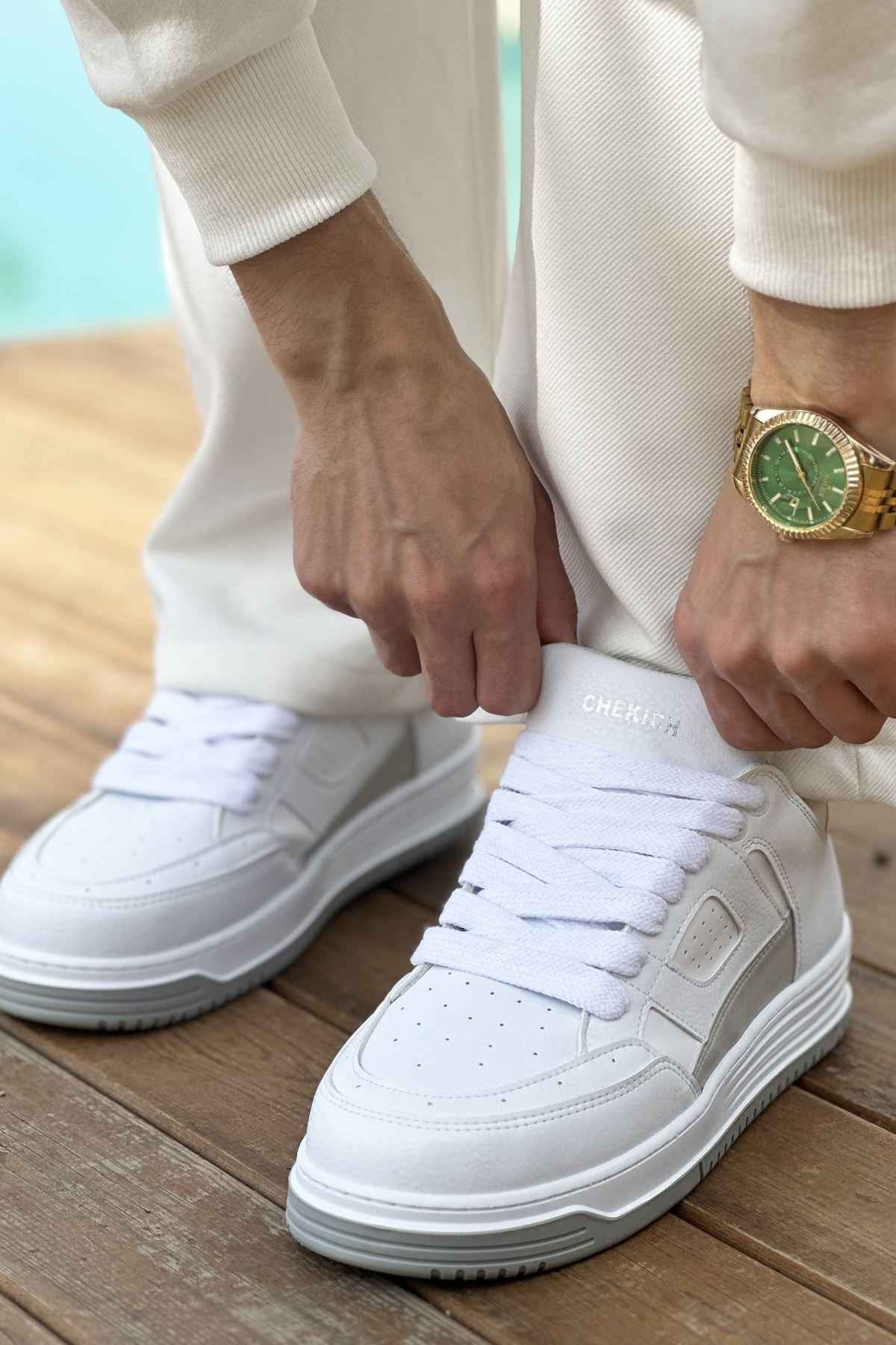 Men's white sneakers on feet with lace-up closure and perforated toe box