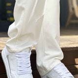 Men's white low-top sneakers with laces and side logo detail on steps