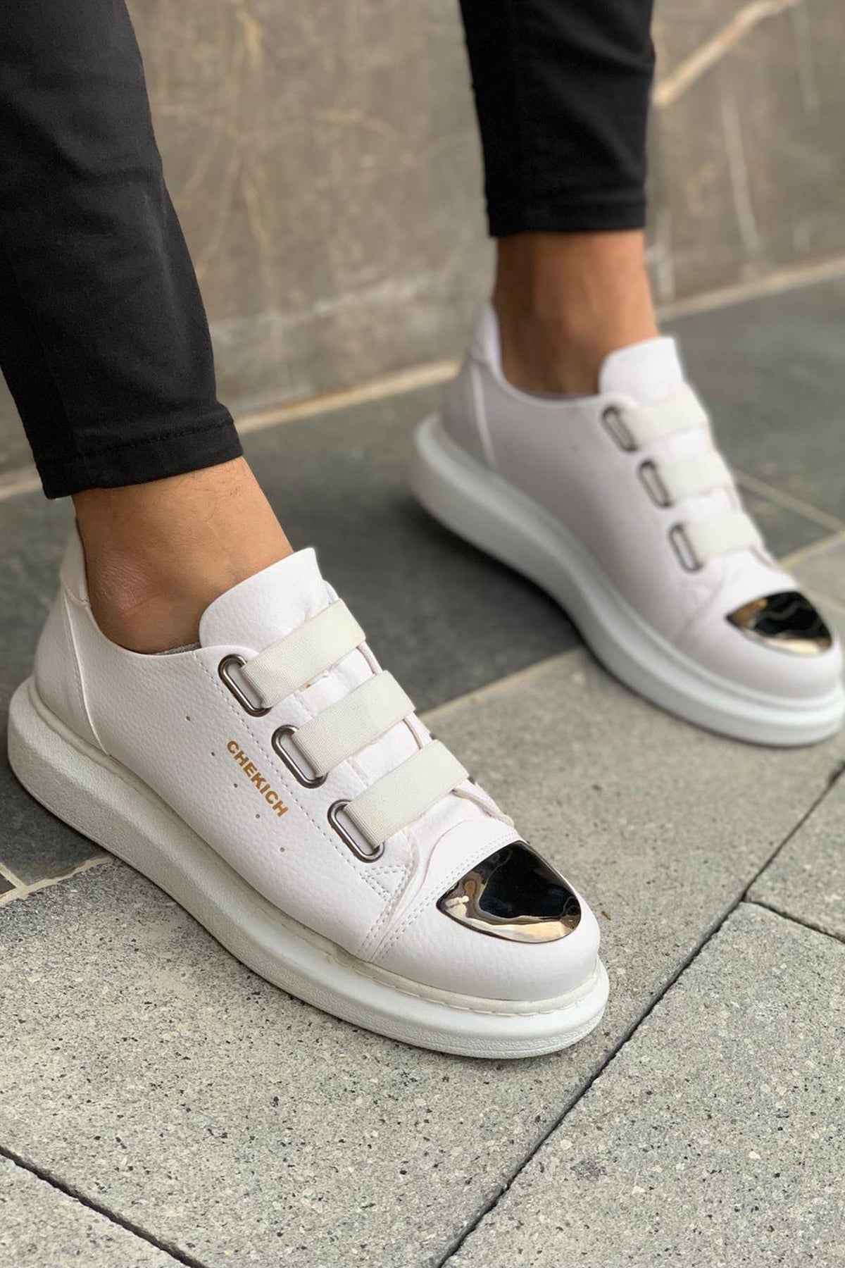 Men's white sneakers, side view with buckled strap and dark oval detail