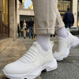 White sock-style sneakers with ribbed knit collar and chunky sole, walking pose