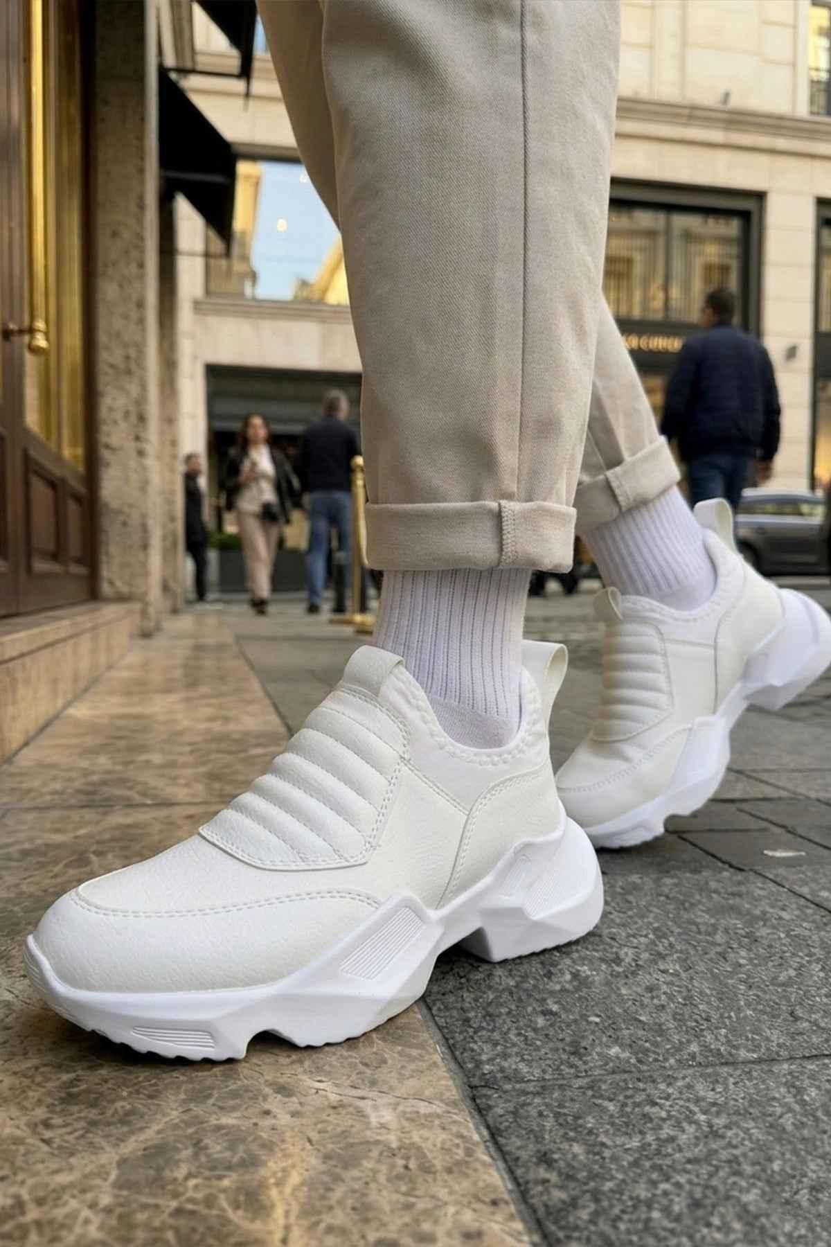 White sock-style sneakers with ribbed knit collar and chunky sole, walking pose