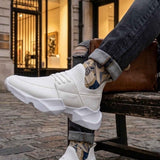 Men's white sneakers with thick platform sole, resting on a wooden bench