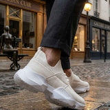 Men's white sneakers with textured upper and chunky sole, side profile on pavement