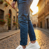 White low-top sneakers with lace-up front, worn with blue jeans