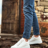 White low-top lace-up sneakers, side view with blue jeans