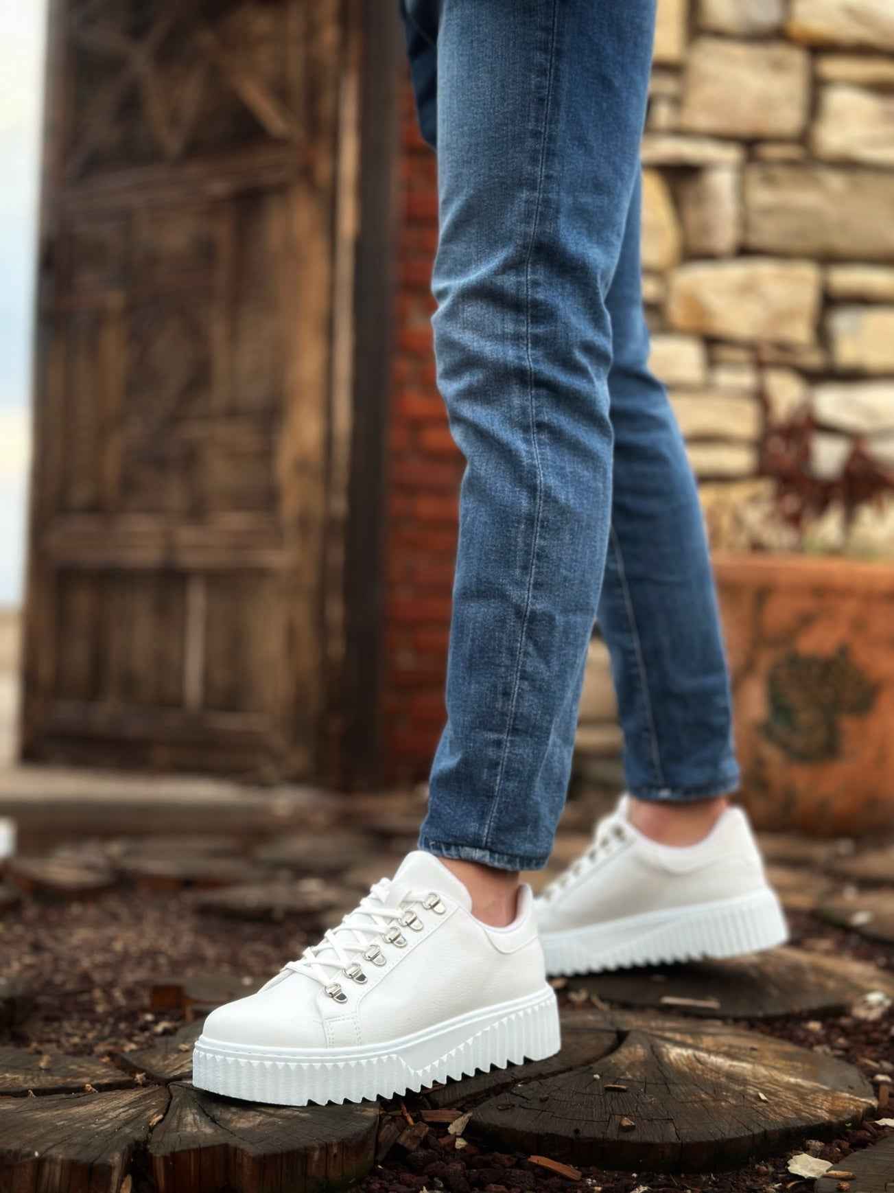 White low-top lace-up sneakers, side view with blue jeans