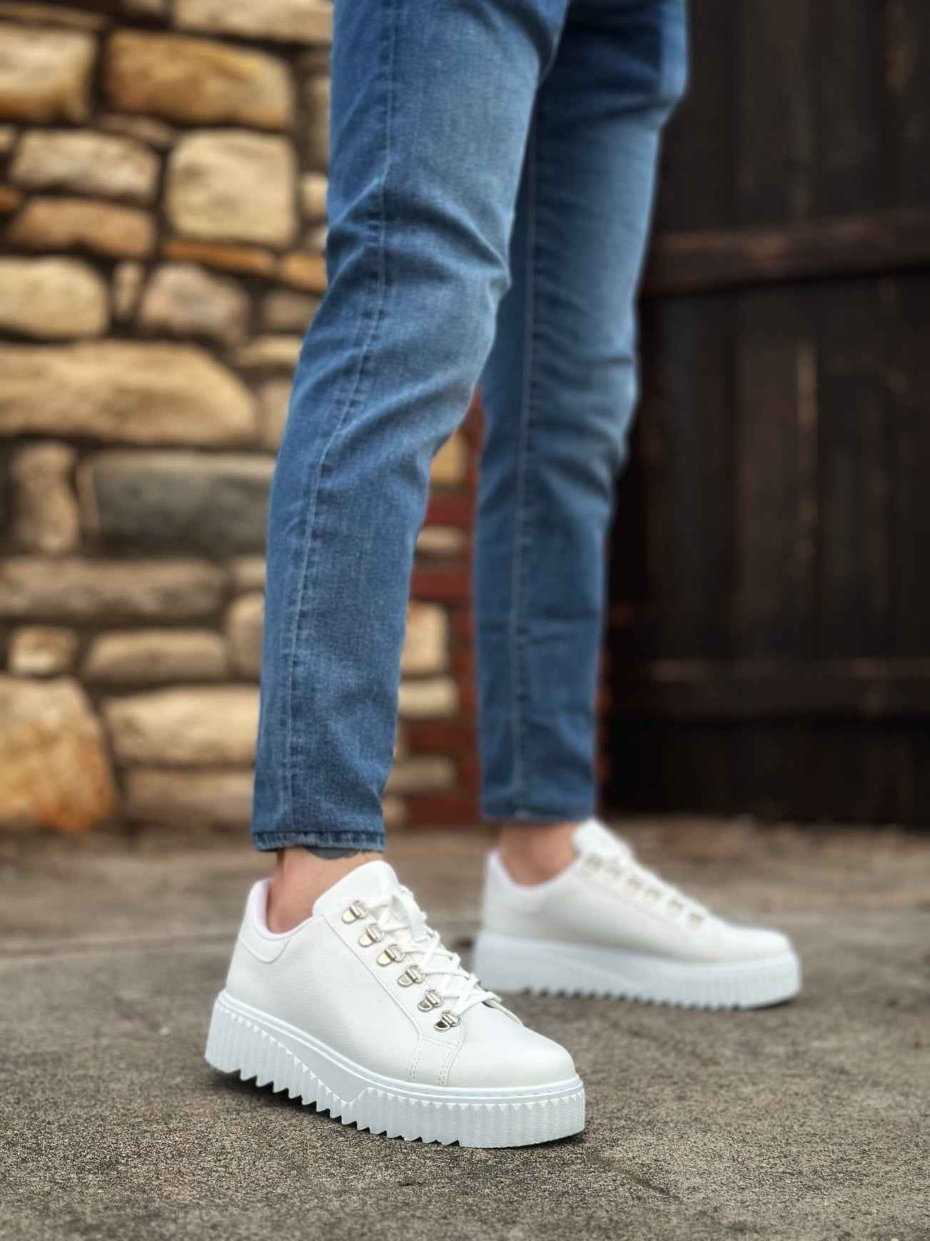 White low-top sneakers with lace-up front, worn with blue jeans