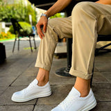 White low-top lace-up sneakers on feet, worn with cropped khaki pants