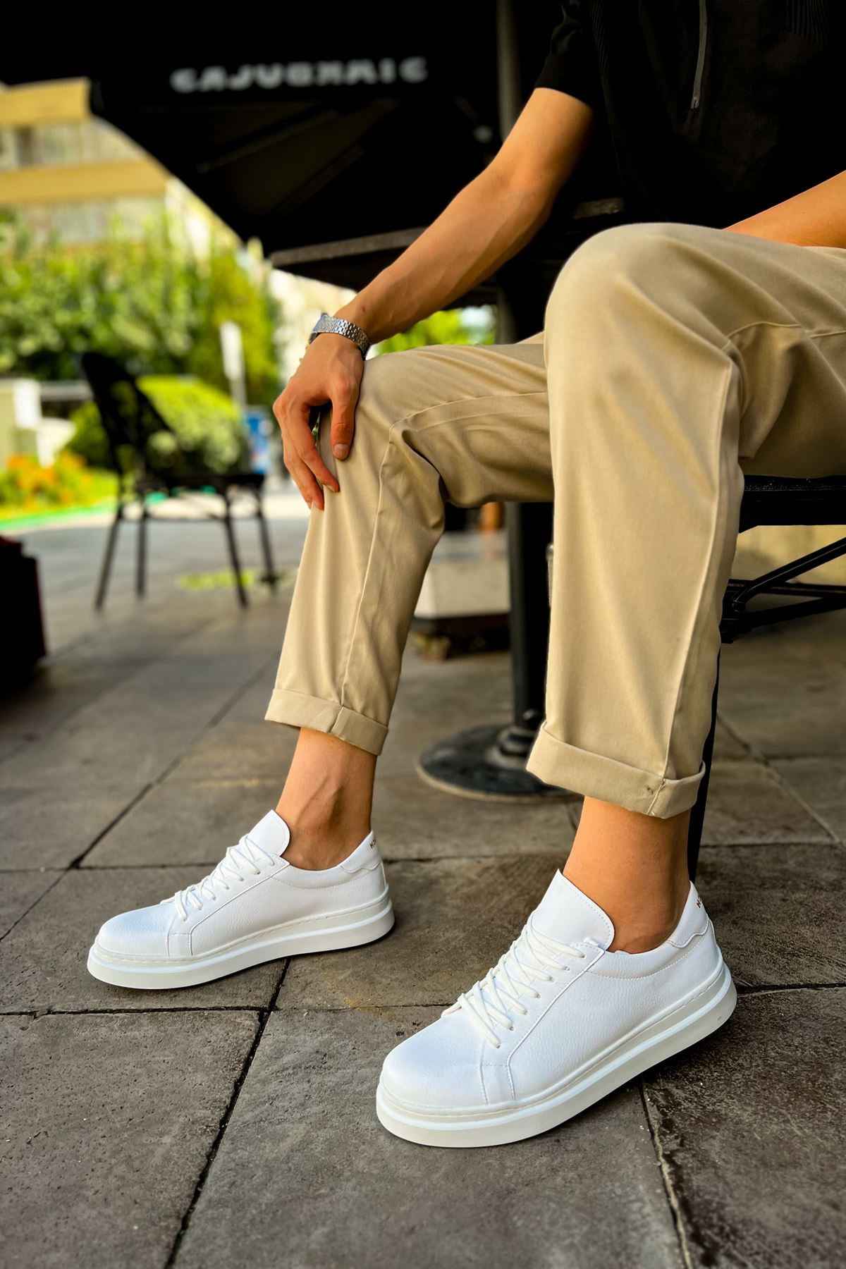 White low-top lace-up sneakers on feet, worn with cropped khaki pants