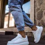 White low-top sneakers on wooden steps, lace-up with smooth upper