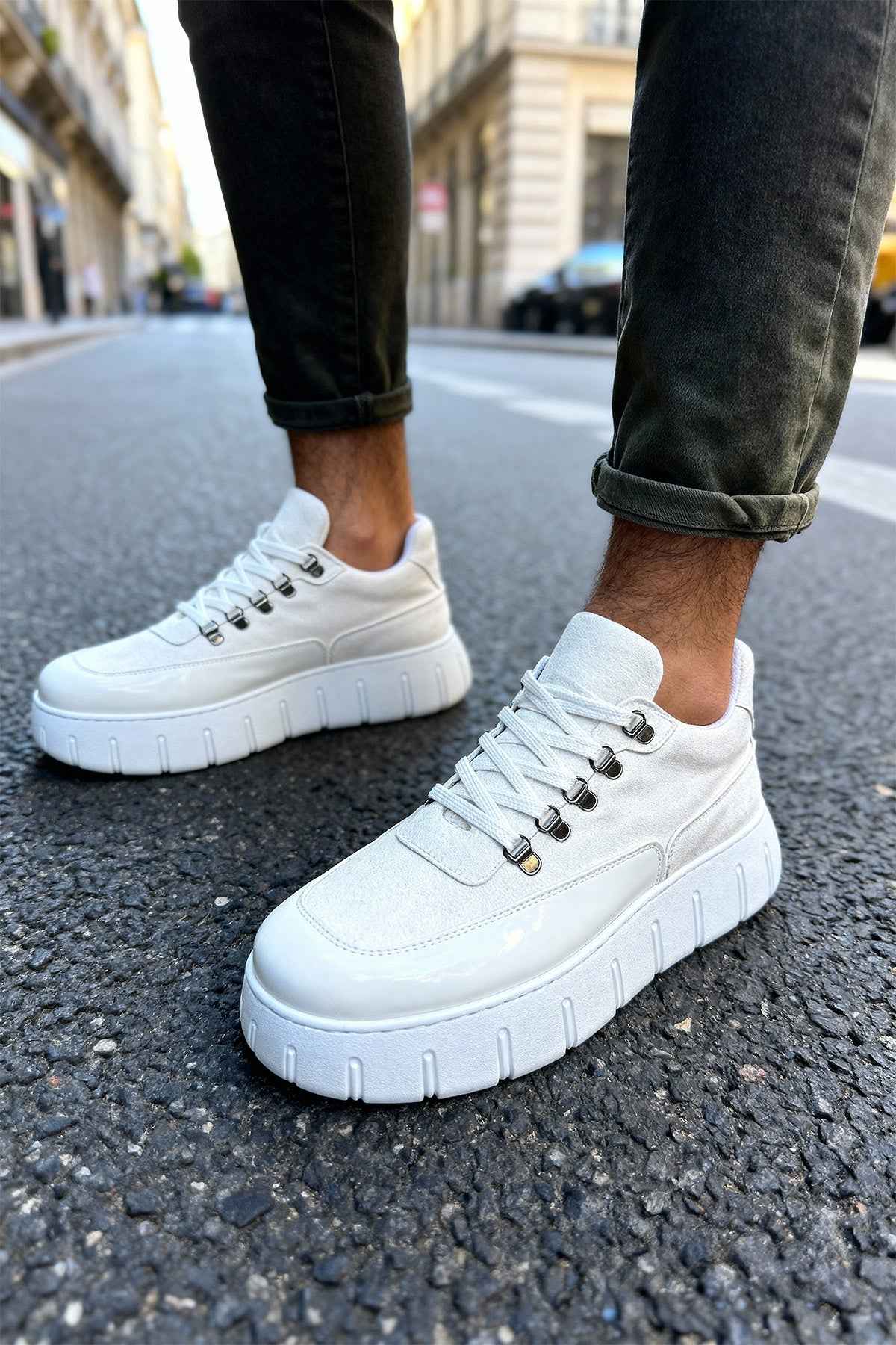 White suede lace-up sneakers with platform sole, front side view on pavement.