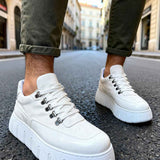 White suede lace-up sneakers with chunky sole and jeans cuffs, angled view.