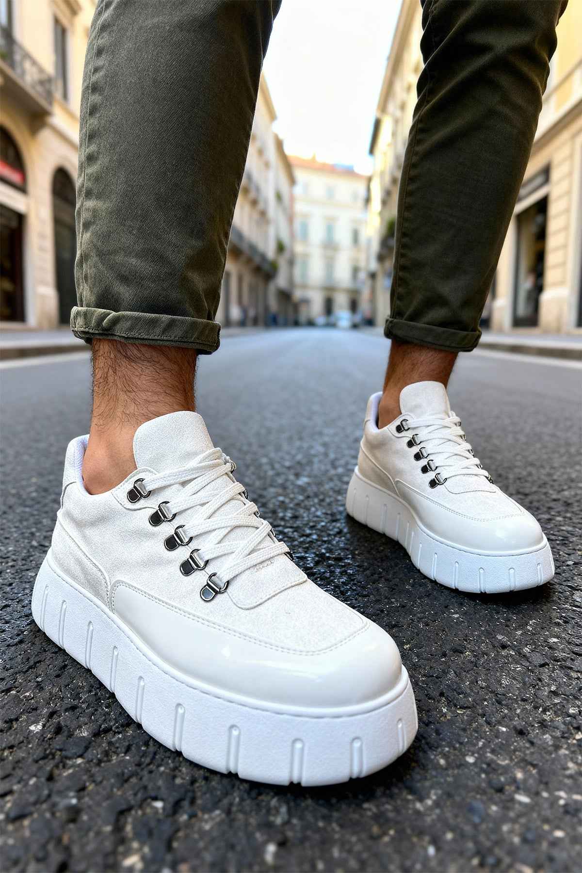 White suede lace-up sneakers with chunky sole and jeans cuffs, angled view.